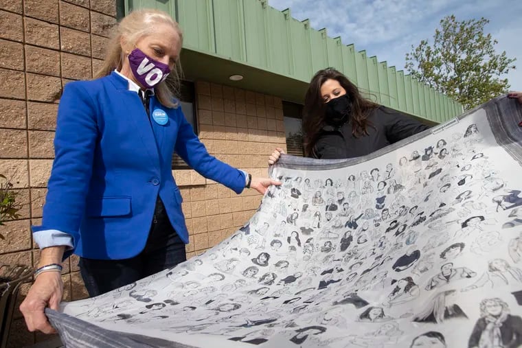 Congresswoman Mary Gay Scanlon, left, shows off a scarf that features the women who were voted into office in 2018, like herself, as she stops at a polling location in Brookhaven, Delaware County, PA on Nov. 3, 2020. Gabby Richards, an aide to Scanlon, is right.