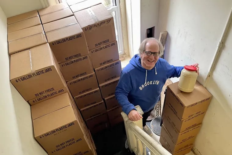 Deli veteran Russ Cowan, stands with a ton of mustard packed in bulk in a storage area at his Famous 4th Street Delicatessen. Rising prices for packaging and shipping forced him to abandon the small bottles he used to purchase. Another ton awaits him at his pickle guy's warehouse in the Bronx.