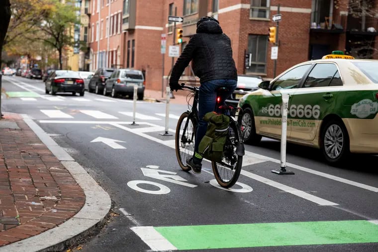A biker rides along the sectioned bike lane along Spruce Street near Ninth Street where flex posts are placed on Wednesday, Nov. 20, 2019. Society Hill has consistently been allowed to circumvent Philadelphia's zoning laws by discouraging apartments and increasing the parking requirements for construction. In addition, the civic association blocked the installation of flex posts on the Pine and Spruce bike lanes.