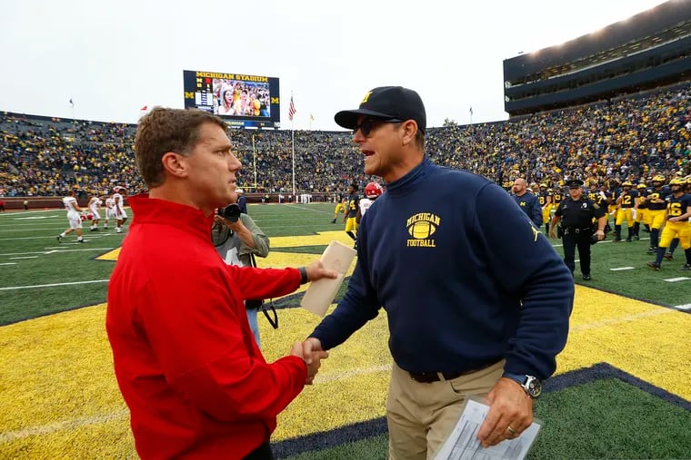 Rutgers head coach Chris Ash (left) and Michigan head coach Jim Harbaugh shake hands after the Wolverines' 52-0 blowout win over the Scarlet Knights in Ann Arbor.