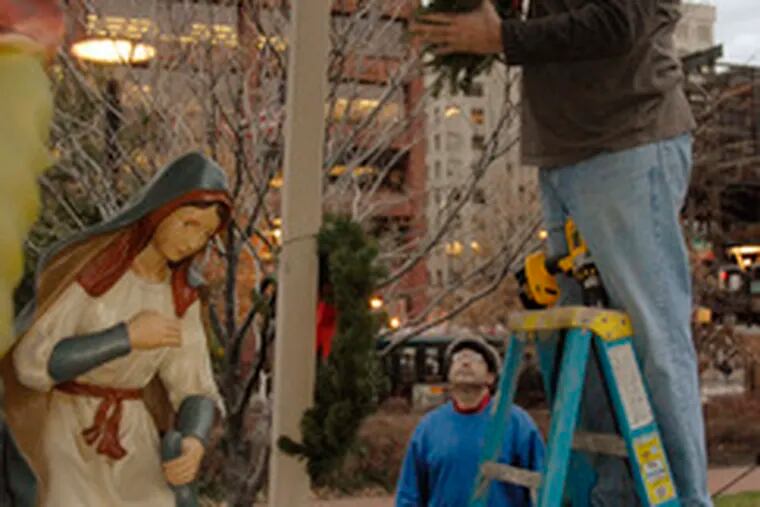 Ancient Order of Hibernians member Tony Nahill affixes a wreath to the Nativity that was vandalized when the baby Jesus was stolen from a creche near Fifth and Market Streets.