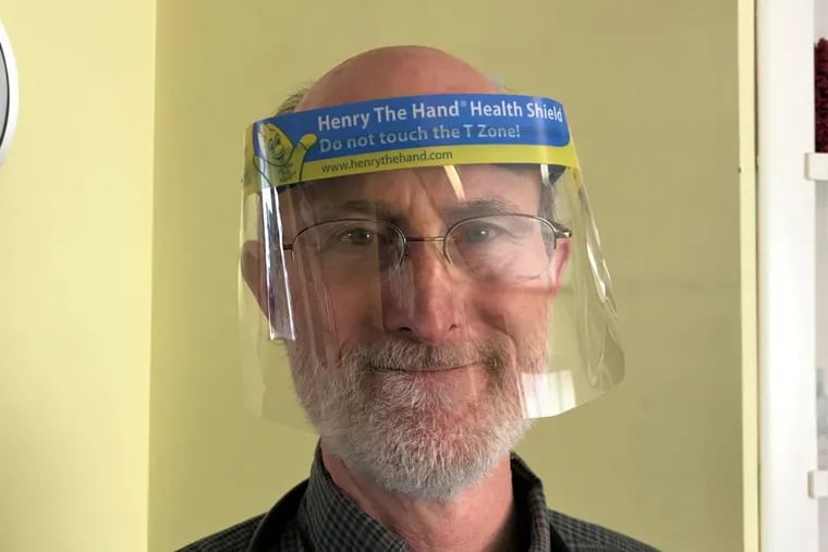 Dr. Will Sawyer, a family doctor in Sharonville, Ohio, and the founder of the Henry the Hand Foundation, models the Henry the Hand Health Shield, which he says can be used to teach people not to touch the mucous membranes of the eyes, nose, and mouth.