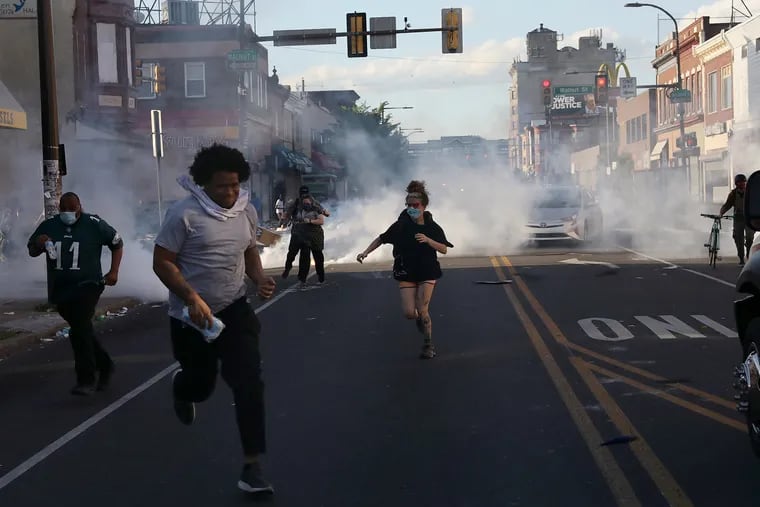 Protesters run as police fire multiple canisters of tear gas toward them at 52nd and Walnut Streets in West Philadelphia on May 31, 2020. City Councilmember Helen Gym has introduced a bill to ban the use of tear gas, pepper spray, rubber bullets, and other "less-lethal" munitions during protests.