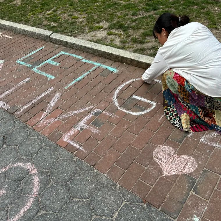 University of Pennsylvania sophomore and student activist Eliana Atienza writes "Let Gaza Live" in chalk at the school's College Green at an event sponsored by the Free Palestinian School.