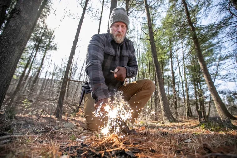 Using the back of his hunting knife, Dan Wowak scrapes downward on a ferro rod,creating a very hot, glowing spark that ignites the dry grass he has piled on the ground and starts the process of building a fire in the woods. Wowak, of Schuylkill County, Pa., is a survival guru who runs camps for teaching survival skills and has a YouTube channel where he shares his knowledge.