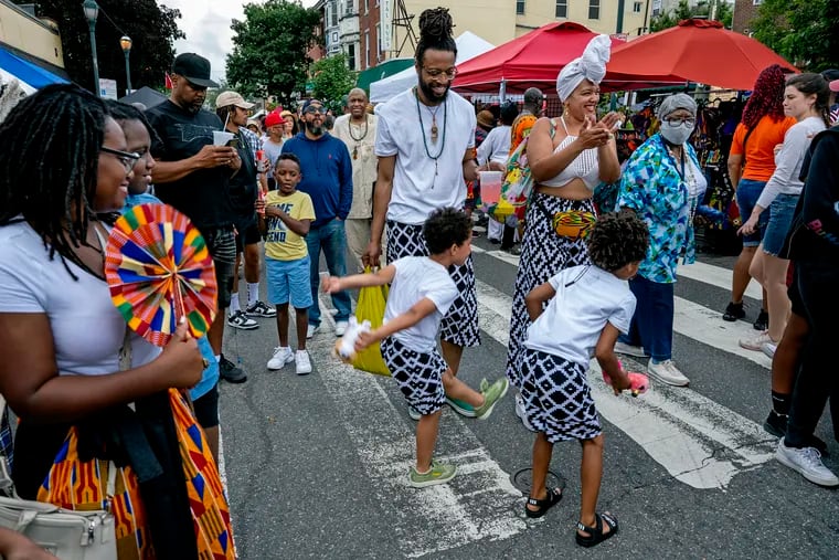 Courtnee and Heather Thomas-Owens pause on South Street so their son and nephewm both 6, can dance, during the annual Odunde Festival June 12, 2022, bringing a taste of Africa to one of Philadelphia's oldest, historically African American neighborhood.
