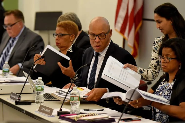 Members of the School Reform Commission receive copies of charter school reports during a recent meeting to determine the fate of nine city charter schools.  Photographer