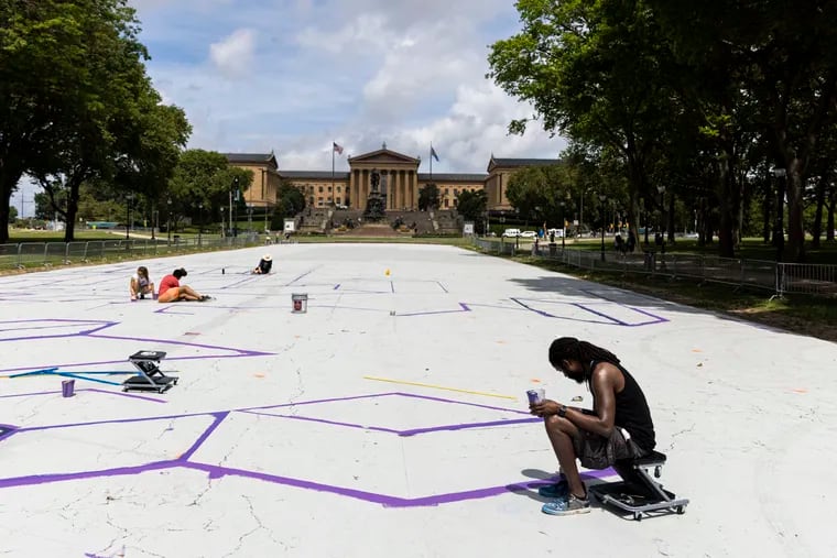 Felix St. Fort (right) is the lead artist for a 'Welcome back, Philly' ground mural at Eakins Oval. A public paint day was cut short by rain Saturday, but St. Fort and others will continue the work throughout the week, aiming to finish in time for July 4 festivities.