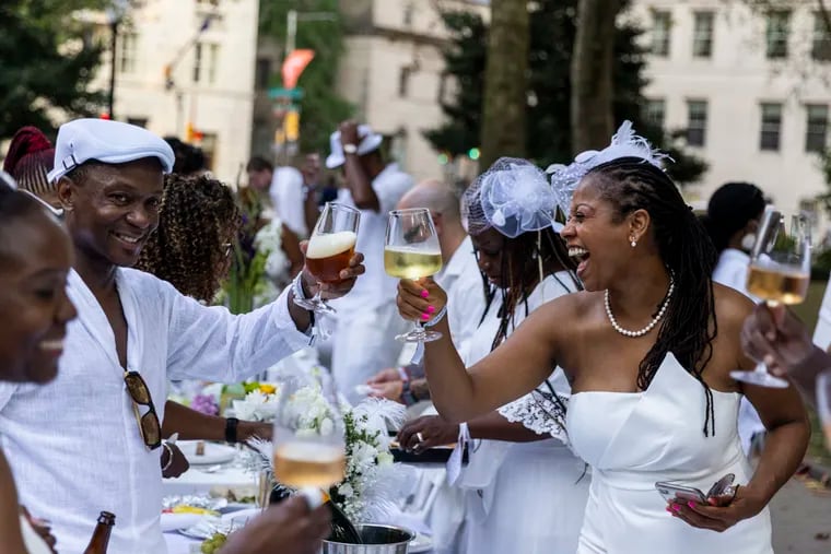 Lisa Wilson, of Laurel, Md., cheers to cups of wine with friends at the annual Diner en Blanc at Rittenhouse Square Park in Philadelphia, Pa., on Thursday, Aug., 12, 2021. This is Wilson’s first time and she is visiting her friends in Philadelphia. Over the course of the evening, guests experience the beauty and value of their city’s public spaces, enjoying music, food, and entertainment.