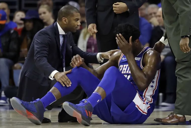 Joel Embiid lies on the court after colliding with teammate Markelle Fultz during Wednesday&#039;s game vs. the Knicks.