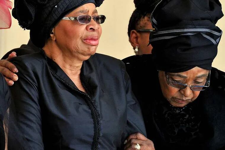 PHOTOS: ASSOCIATED PRESS Mandela's widow, Graca Machel (left), and Winnie Madikizela-Mandela, his second wife, watch as the former president's casket arrives at his burial site yesterday.