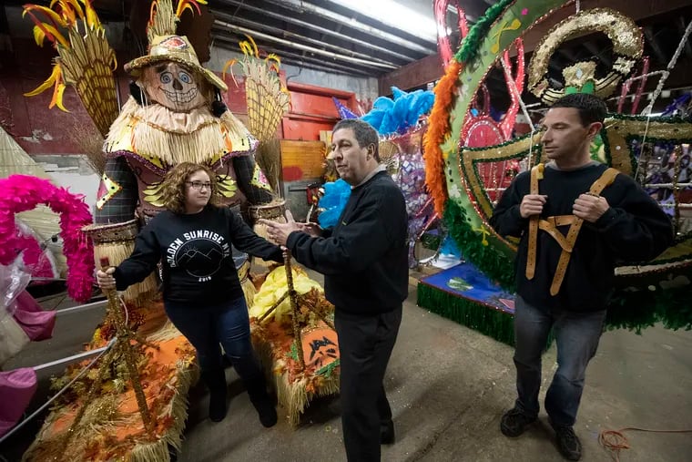 Golden Sunrise members Lila Horowitz, Jack Cohen, center, and Mike Rubillo show the wheeled frames and padded harnesses that enable Mummers to wear their heavy costumes.