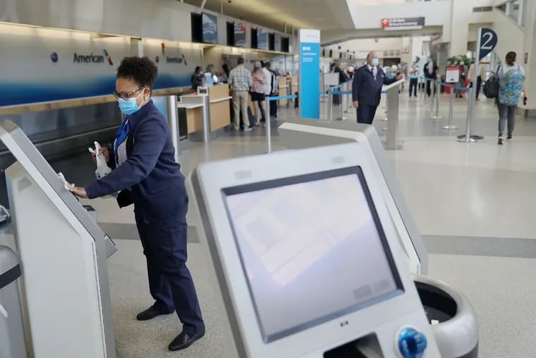 An American Airlines customer service supervisor wipes down a kiosk at Philadelphia International Airport on June 30. On Monday, the airport will be allowed to start receiving passenger flights from Europe again.