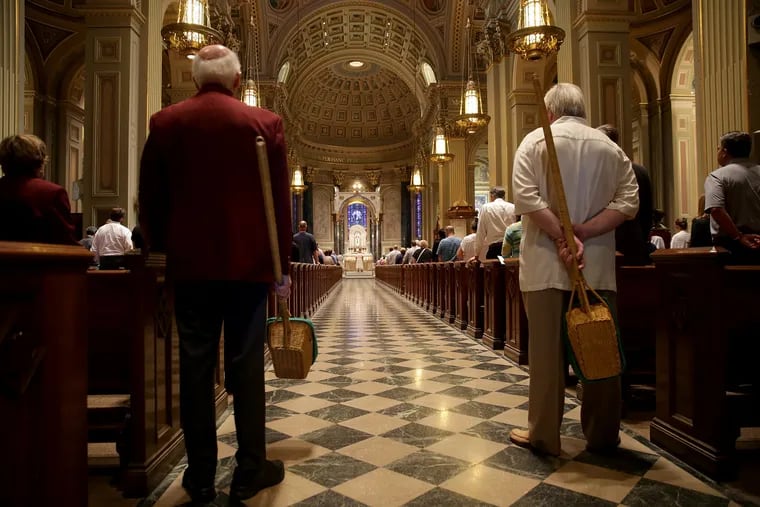 Ushers wait to collect donations during a mass for the Assumption of the Blessed Virgin Mary at Cathedral Basilica of Saints Peter and Paul in Philadelphia, PA on August 15, 2018.