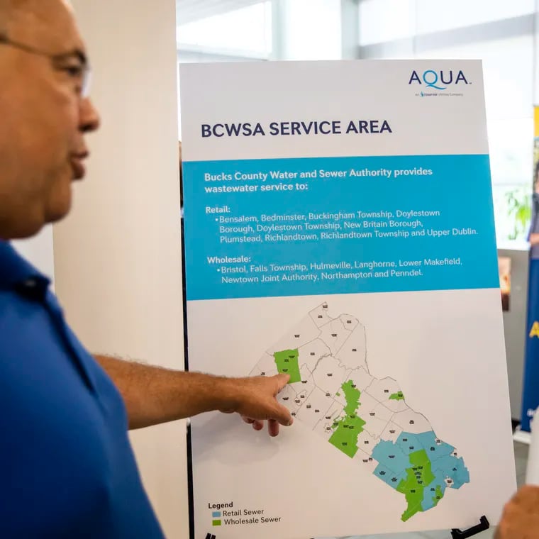 Larry Woodson (left), of Plumstead Township, and Brian Haley, of Richland Township, talk over one of the signs displayed by Aqua America during an open house held by Bucks County Water and Sewer Authority in Perkasie in 2022.