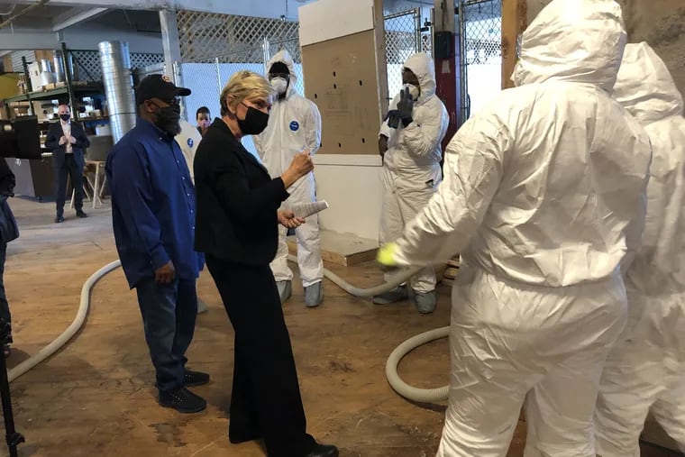 U.S. Secretary of Energy Jennifer M. Granholm (center) on a tour of the Energy Coordinating Agency, a nonprofit on W. Clearfield Street in Philadelphia's Kensington section.  The facility trains disadvantaged youth and adults in green energy jobs.  Head trainer Jackie Robinson, left, explains how the students are trained to insulate.