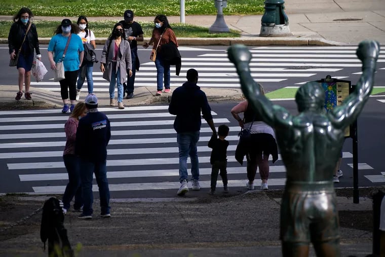 Visitors cross the street in front of the Rocky Statue outside the Philadelphia Museum of Art in May 2021.