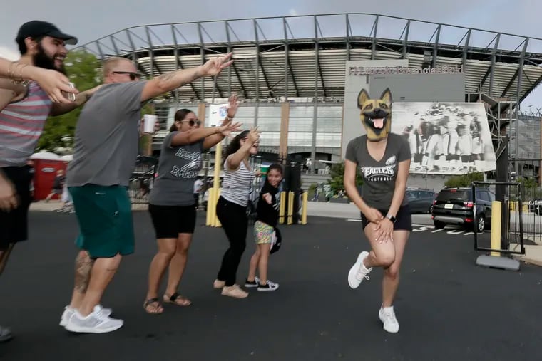 Eagles fan Veronica Ortiz of Philadelphia leads an Eagles cheer wearing an Underdog mask before heading into Lincoln Financial Field for the open Eagles practice on Sunday, Aug. 5, 2018.
