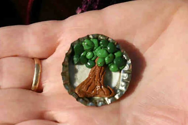 A tree pin made of clay in a bottle cap, given to Tree Tenders of exceptional accomplishment. (Charles Fox / Staff Photographer)