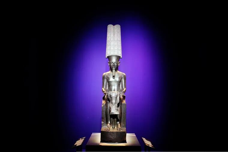 A statue of "The god Amun protecting Tutankhamun" is displayed as part of 'Tutankhamun, the treasure of the Pharaoh', an exhibition in partnership with the Grand Egyptian Museum at the Grande Halle of La Villette in Paris, France, Thursday, March 21, 2019. (AP Photo/Francois Mori)