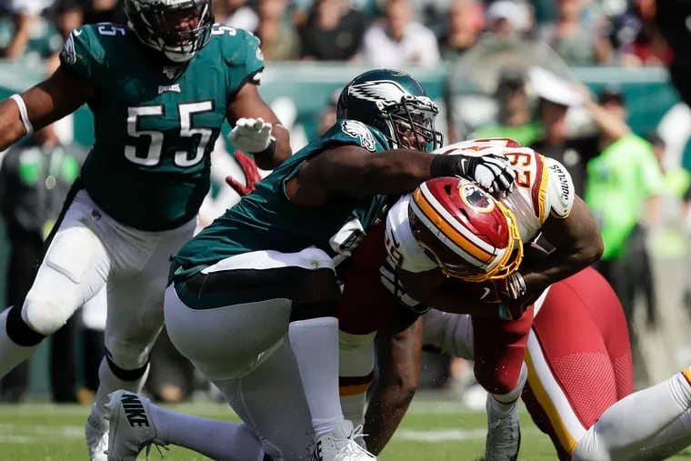 Fletcher Cox wrangles Washington running back Derrius Guice to the ground Sunday as Brandon Graham looks on. Cox, linebacker Nigel Bradham and guard Brandon Brooks did extra work in the preseason as they recovered from injuries and played well in the season-opening win.