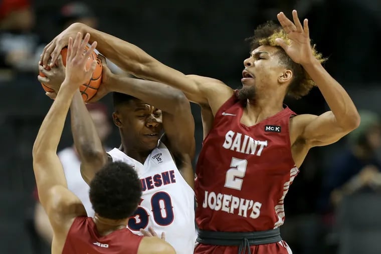 St. Joseph's Charlie Brown Jr. (2) blocks a pass by Duquesne's Eric Williams Jr. (50) during their second-round Atlantic 10 Tournament game at the Barclays Center in Brooklyn, N.Y., on Thursday, March 14, 2019.