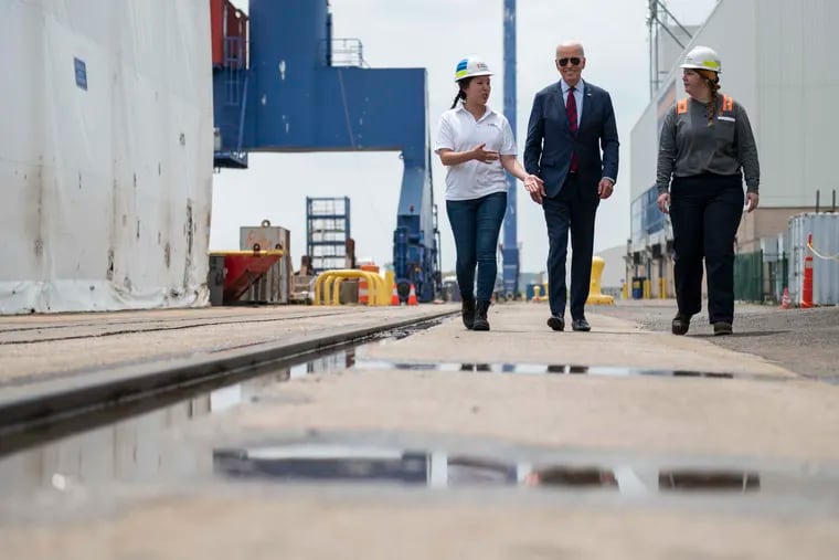 President Biden (center) walks with Philly Ship Yard Apprentice Workers Megan Heileman (left) and Emily Andrewson (right) on Thursday.