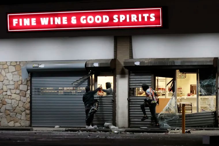 People steal from the Fine Wine & Good Spirits store at 730 Adams Ave. during a night of vandalism in Philadelphia early on Wednesday, Sept. 27, 2023.
