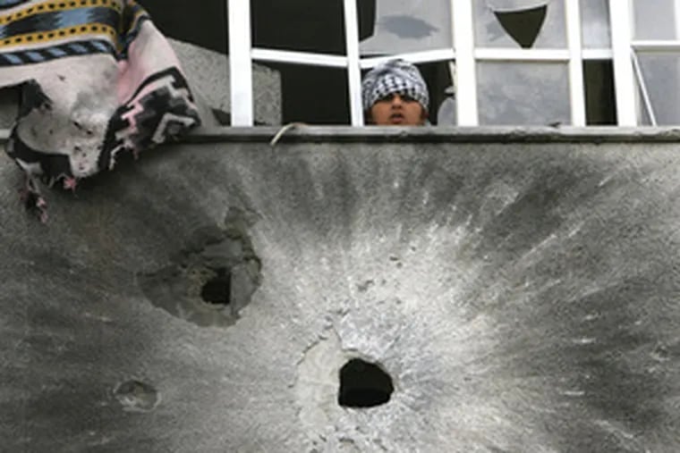 A Palestinian boy looks out over a wall pockmarked by bullets during clashes yesterday in Gaza City.