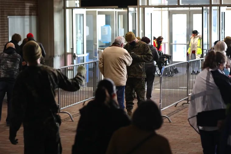 Soldiers check IDs of people as they arrive on the first day of the FEMA COVID-19 vaccination site at the Pennsylvania Convention Center in Center City Philadelphia on Wednesday, March 3, 2021.