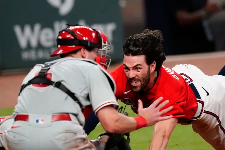 The Braves' Dansby Swanson (right) dives into home plate and is tagged out by the Phillies' Andrew Knapp for the last out of the game on Sunday.