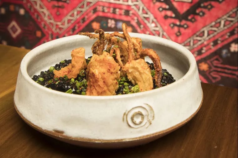 The squid ink rice at Oloroso is topped with fried calamari.
