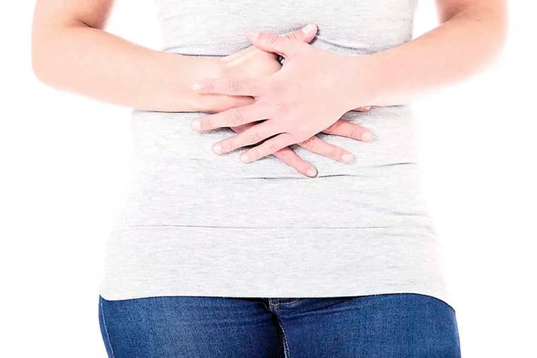 Stock image of a woman clutching her abdomen.