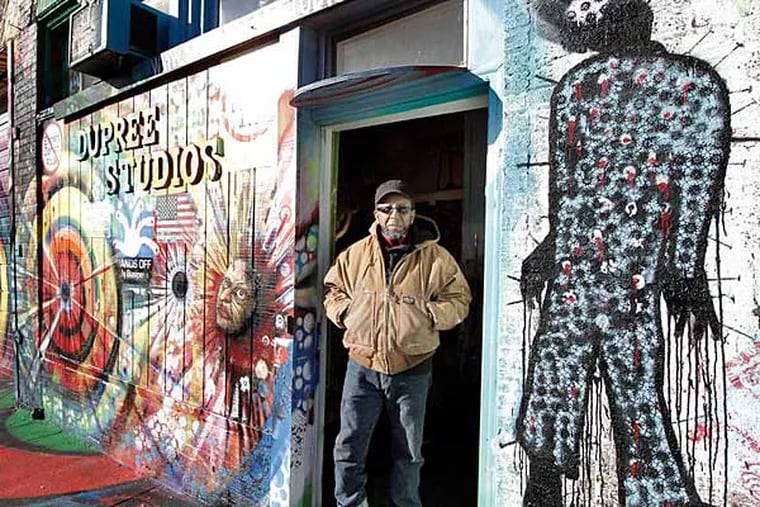 James Dupree outside his studio in the Mantua section of West Philadelphia, decorated with images of persecution. ELIZABETH ROBERTSON / Staff Photographer
