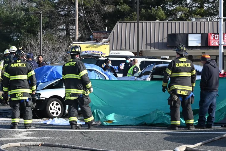 Emergency personnel respond to a motor vehicle collision in Magnolia, N.J. on Wednesday morning. Two people died at the scene and two firefighters were transported to the hospital after a Lawnside Fire Department truck and a car (covered with a tarp) collided at Warwick Road. and White Horse Pike.