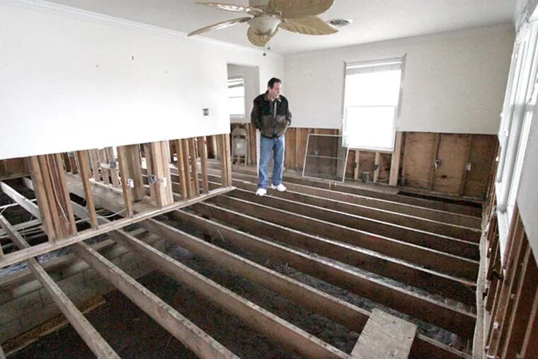 Maurice Corkery of Delaware County stands on floor joists in what used to be the living room of his storm-damaged Ocean, City, N. summer home. (Elizabeth Robertson / Staff Photographer)
