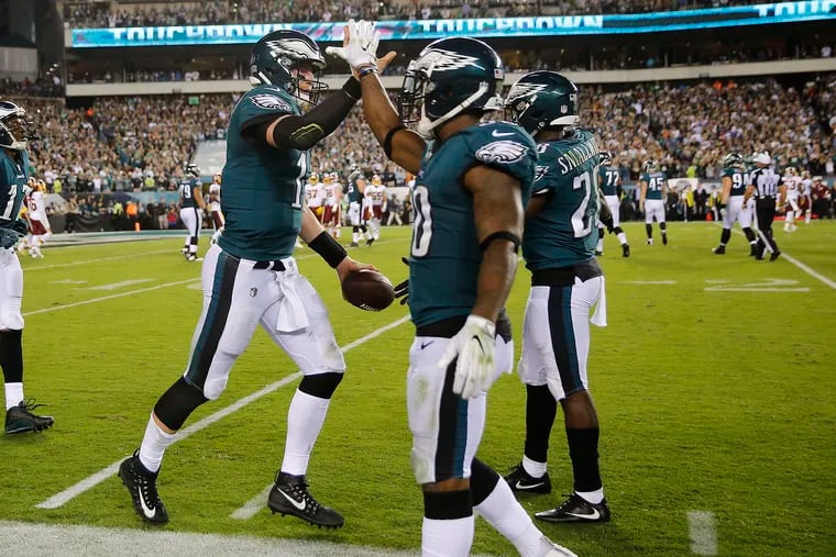 Eagles' Carson Wentz, left, celebrates a 2nd quarter touchdown with Corey Clement, center, and Wendell Smallwood, right, as the Philadelphia Eagles play the Washington Redskins in Philadelphia, PA on October 23, 2017. YONG KIM / Staff Photographer