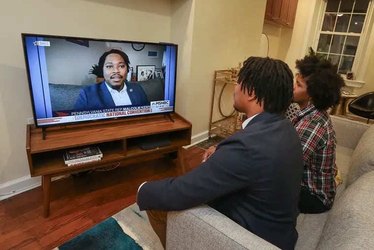 State Rep. Malcolm Kenyatta (left) watches himself help deliver the Democratic National Convention keynote address from his home in Philadelphia on Tuesday with his fiancé, Matt Miller.