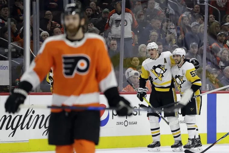 Penguins Evgeni Malkin, (center) and Kris Letang celebrating behind the Flyers' Sean Couturier after an empty-net goal by Malkin on Wednesday.