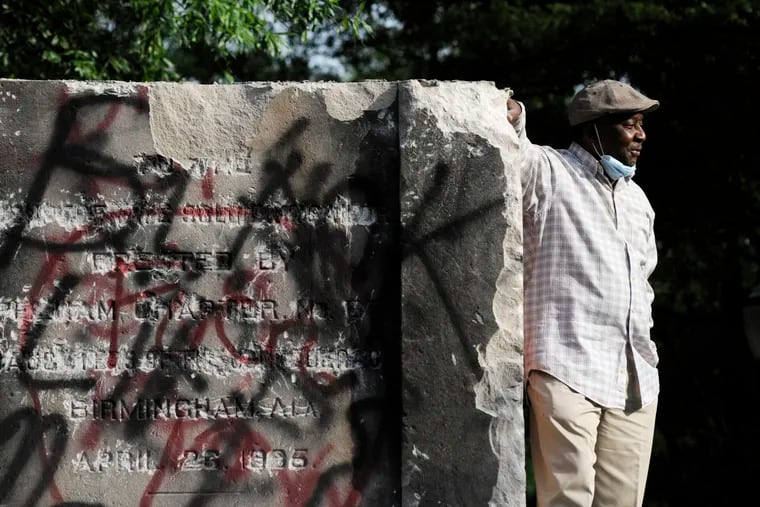 Robert Walker poses for a photograph on the remains of a Confederate memorial that was removed overnight in Birmingham, Ala.
