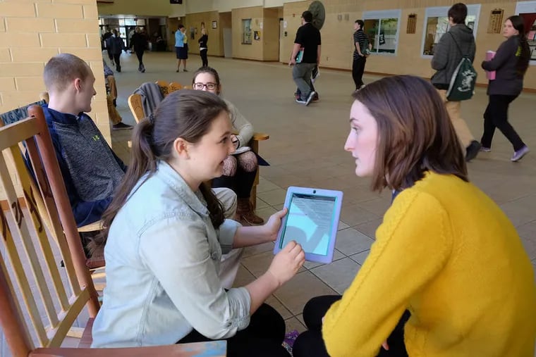 Libby Alfieri (left) and Kellie O'Brien, seniors at Ridley High School, use technology to complete schoolwork between classes. Schools can choose from a plethora of tech offerings, but many of them are untested.