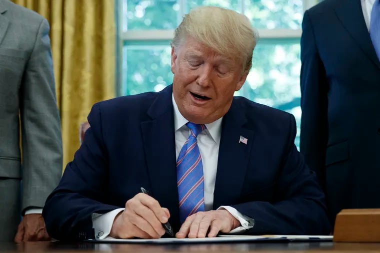 President Donald Trump signs a $4.6 billion aid package to help the federal government cope with the surge of Central American immigrants at the U.S.-Mexico border during a ceremony in the Oval Office of the White House in Washington, Monday, July 1, 2019. (AP Photo/Carolyn Kaster)