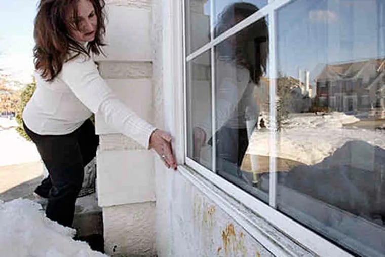 Lisa Ruffner of Voorhees points to windows that she said leaked and allowed mold to form in the moist stucco of the wall. (Elizabeth Robertson / Staff)