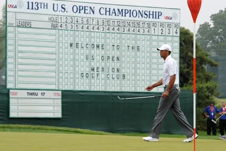 Tiger Woods walks past the leader board at Merion Golf Club during a practice round for the U.S. Open golf championship on June 10, 2013.