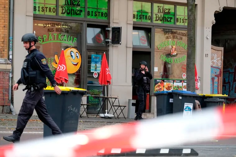 A police officer walks in front of a kebab grill in Halle, Germany, Wednesday, Oct. 9, 2019. A gunman fired several shots on Wednesday in the German city of Halle. Police say a person has been arrested after a shooting that left two people dead. (Sebastian Willnow/dpa via AP)