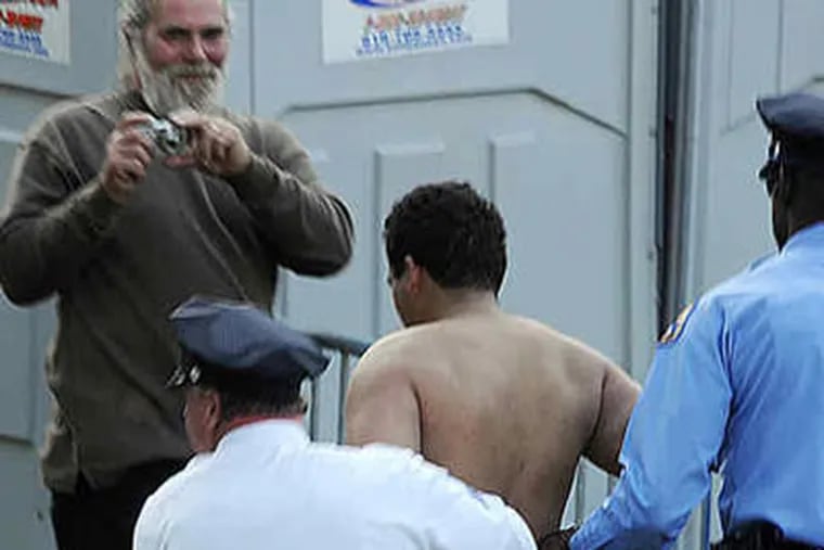 Juan J. Rodriguez is removed in handcuffs from the Obama rally in Germantown after running naked.