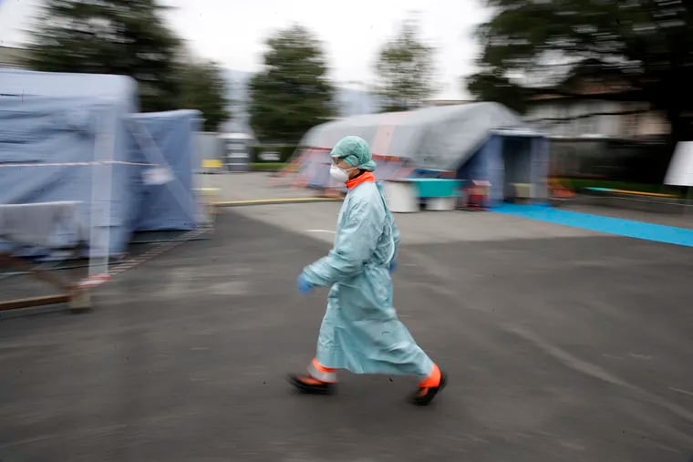 Without immediate and strict containment, a Philadelphia pediatric cardiologist writes that the U.S. will face what Italian health care workers are struggling with as facilities and staff face too many patients to care for them all. Here, a doctor walks at one of the emergency structures that were set up to ease procedures at the Brescia hospital in northern Italy Thursday. (AP Photo/Luca Bruno)