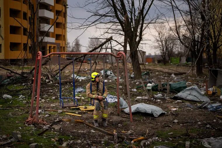 A firefighter sits on a swing next to a building destroyed by a Russian bomb in Chernihiv on Friday, April 22, 2022.
