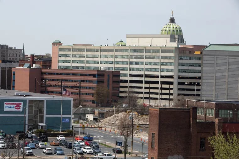 PIctured is the red brick PSERS headquarters, left, overlooking the demolished Patriot News building at 812 Market Street, Harrisburg, Pa. in, 2019. State Capitol dome is at top right. The public school pension system has acquired and demolished a string of Harrisburg properties that now sit vacant, part of a wide-ranging investment portfolio that underperformed its own benchmarks from 2011 to 2020. PSERS investments are now the subject of federal and internal investigations. For the Inquirer/Kalim A. Bhatti