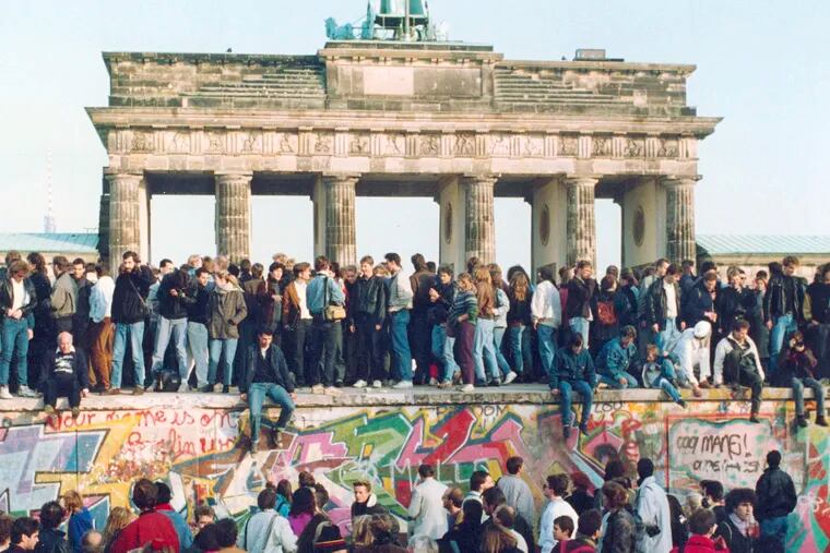 FILE - In this Friday, Nov. 10, 1989 file photo, Germans from East and West stand on the Berlin Wall in front of the Brandenburg Gate in Berlin. (AP Photo, File)